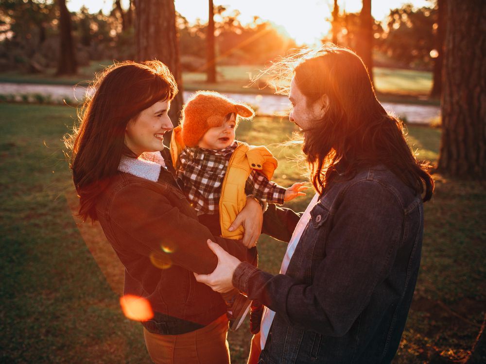Parents playing with their child in a sunlit park