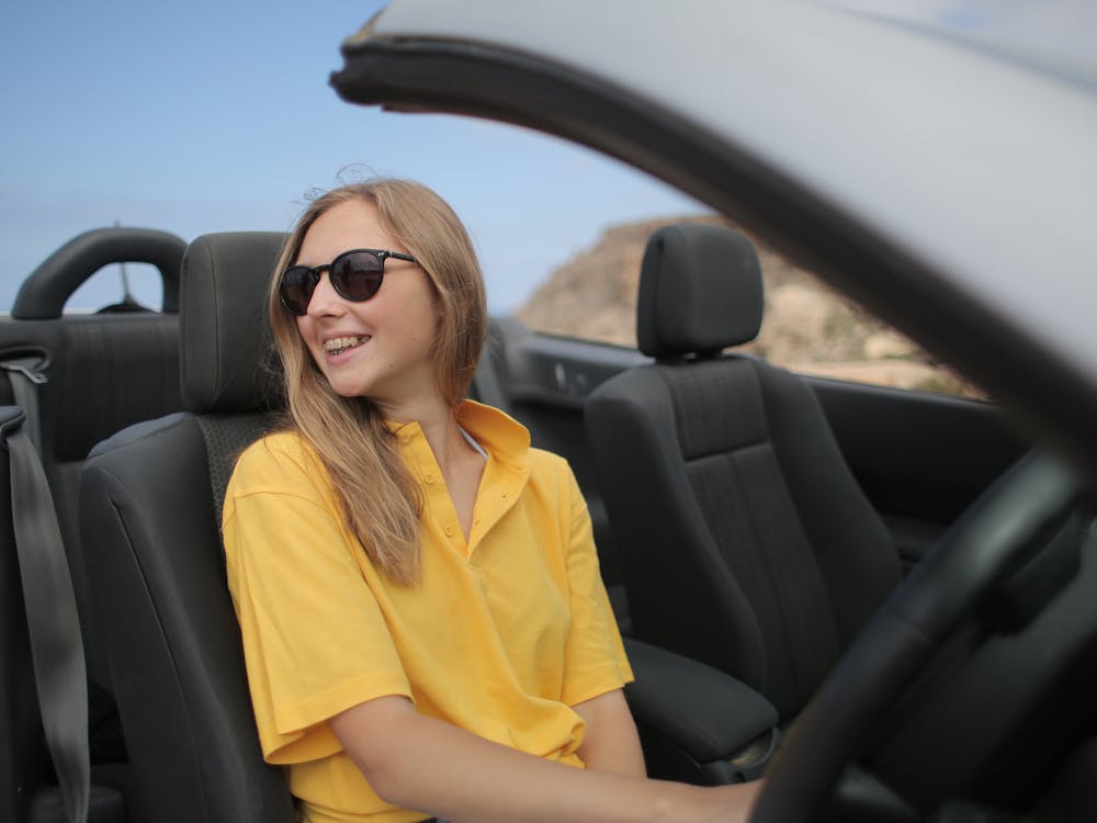 Smiling woman driving a convertible on a coastal road