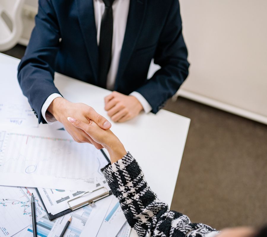 Two professionals shaking hands over a desk